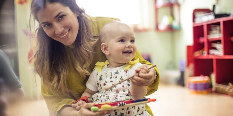 Woman holding baby in classroom